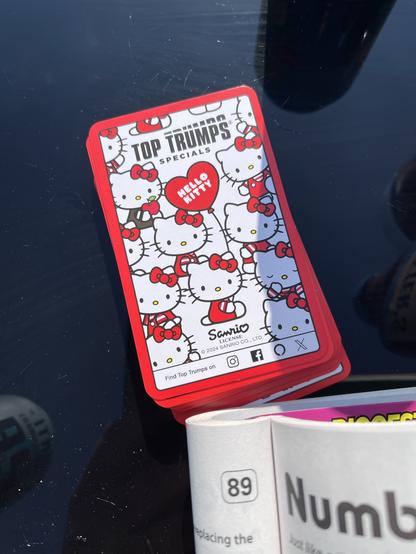 A deck of Hello Kitty-themed Top Trumps cards on a glass, outdoor table top.