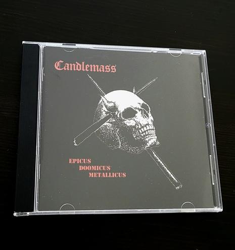TW description might be slightly disturbing

A CD album on a dark background. Album cover is black, with a white horned skull being pierced by two stakes from the left and from underneath. Band name Candlemas is written in red Fraktur script in the upper left corner of the cover, while album name Epicus Doomicus Metallicus is printed in smaller capital block letters under the left side of the skull.