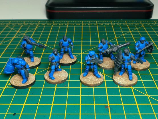 A photo of 8 miniatures partly painted in blue and grey.