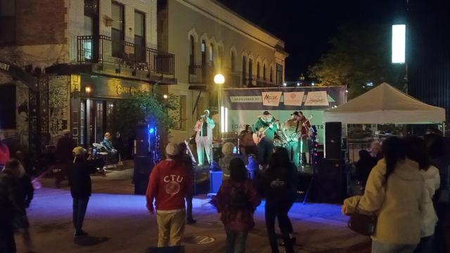 An outdoor music stage at night with people dancing.