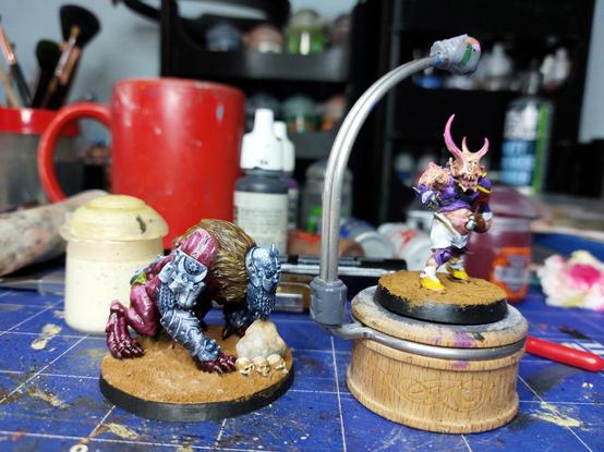 Trench crusade lion overlooking a pile of skulls next to a rock and blood bowl rotter with some conversions on a pile of mud.