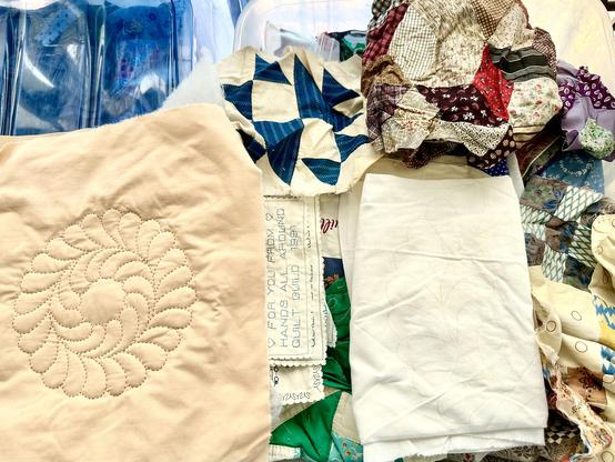 A clear bin being sorted for quilted pieces and patchwork blocks to save for new small projects. Various old and new cloth pieces, various colors.