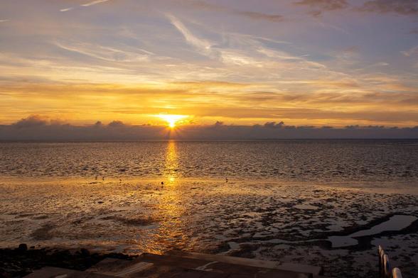 Strand an der Nordsee im Sonnenuntergang, der Blick geht über das Wattenmeer