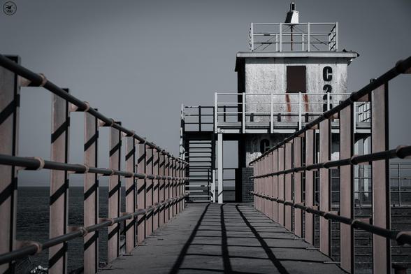 Shot following railings leading up to old harbour tower, desaturated shot to give grey appearance