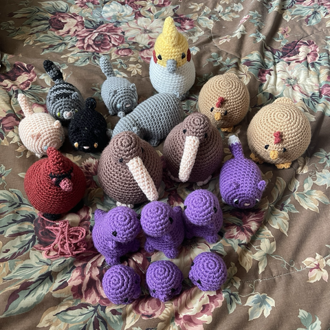 Crocheted plushies: five kitties, one cockatiel, two chickens, two kiwis, one cardinal, three t-rexes, and three squids
