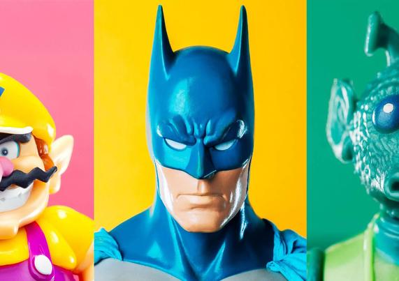 Three toy figures are displayed side by side: Wario on a pink background, Batman on a yellow background, and Greedo on a teal background.