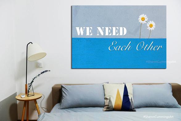 Art that reads We Need Each Other with two white daisies on a blue background in a bedroom furniture setting by artist Sharon Cummings.