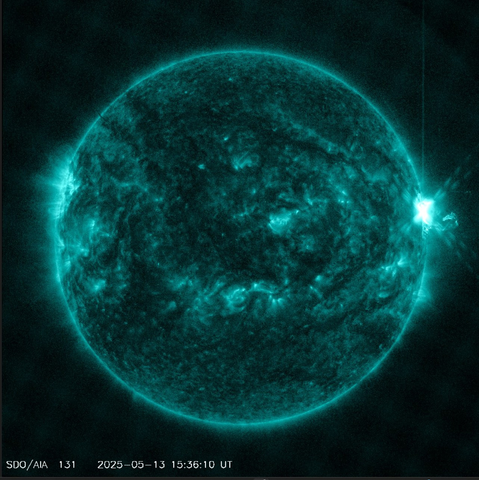 The solar disc, seen in a special filter by the SDO satellite. This surface of the Sun in this image is granular. The colour of the twisted light is teal. There are dark patches as well. To the right, on the limb, an extended structure emerges from the surface and extends into space.