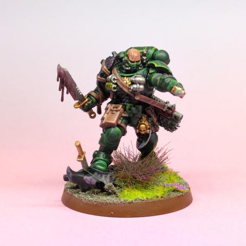 A space marine in dark green armour with a knife in each hand
