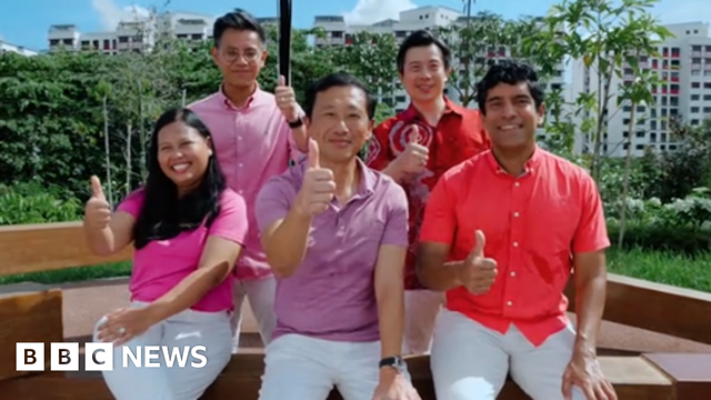 A screenshot of a TikTok video by Ong Ye Kung, showing him and four other PAP members wearing white pants and red or pink shirts. They are sitting on a park bench and giving the thumbs-up sign.