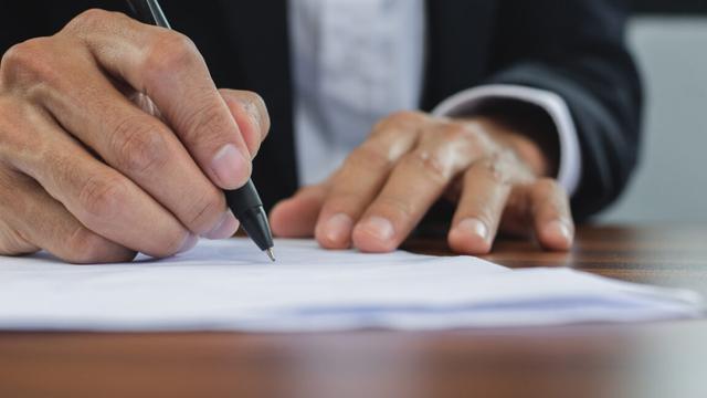 Close-up of hands signing a document with a pen