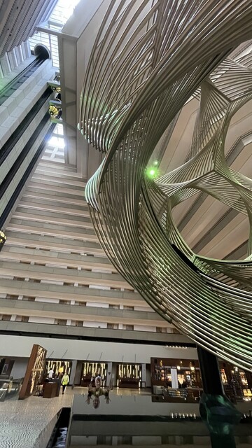 Hyatt Regency lobby infinity fountain with spiral sculpture. Annie reflects herself in the glass smooth water. 