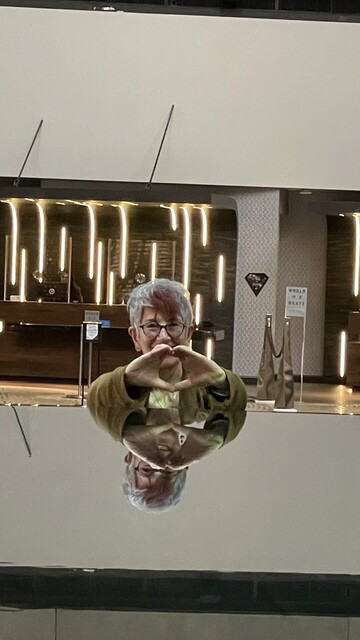 Closer shot of Annie Fox reflecting in the glass smooth fountain surface. Reception desk in the background. 