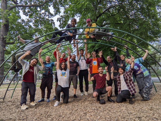 A third photo of the group, with everybody (but the people on top of the structure) putting their hands up now. Emilio is shooting finger pistols into the air like it's the wild west, while Nat is living the dream of photobombing her boss with some sneakily added bunny ears.