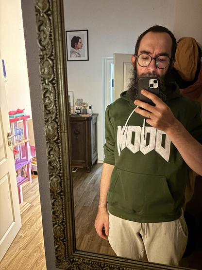 Me in front of a mirror wearing a dark green hoodie spelling out MOOD in the doom font. It’s a DOOM hoodie obviously.