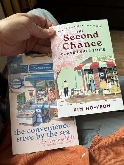Two books. On the left „The Convenience Store by the Sea” by Sonoko Machida and on the right „The Second chance Convenience Store”  y Kim Ho-Yeon! Both feature drawings of windows and entries of a particular store in a somewhat comparable style.