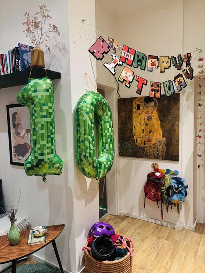 Birthday decoration for a ten year old child. There are two balloons with the Minecraft creeper texture as a One and a Zero. Additonally, there’s a banner that spells Happy Birthday and every character is somewhat a Minecraft item/character in the shape of the letter.