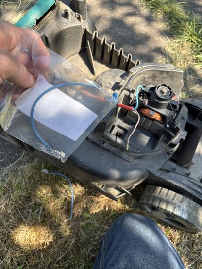 Open lawn mower with its electro motor visible.
I’m holding a small plastic bag with a new thermo sensor while the old one is unplugged.
