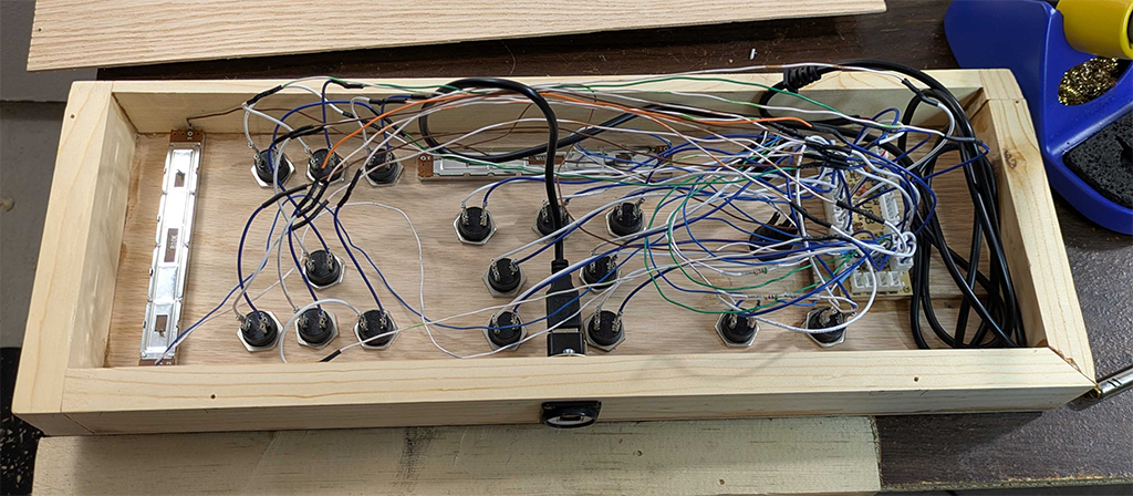 Interior shot of the button box showing a tangle of wires connecting the buttons/switches/potentiometers to the PCB.