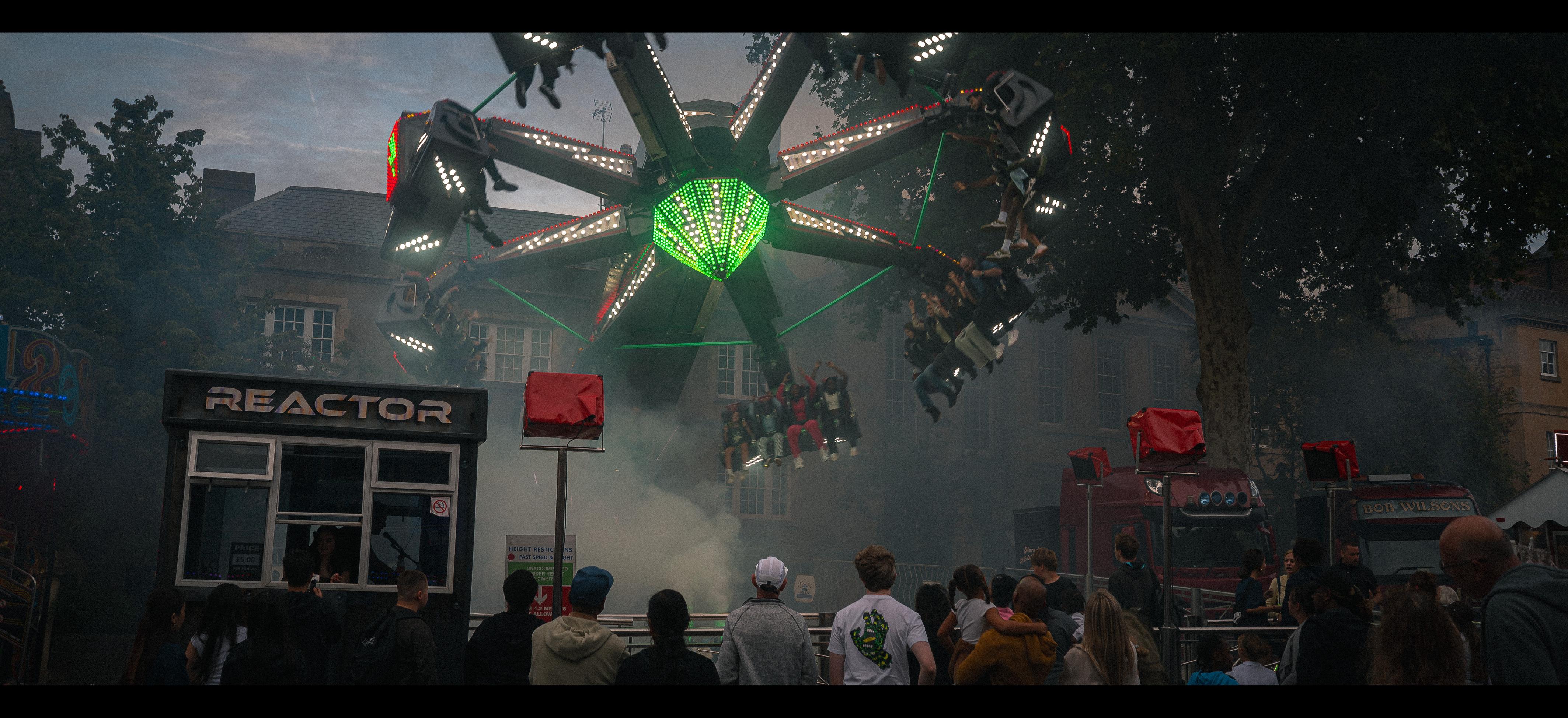 Audience stare up at a ride that looks like a landing alien craft bears down upon them.