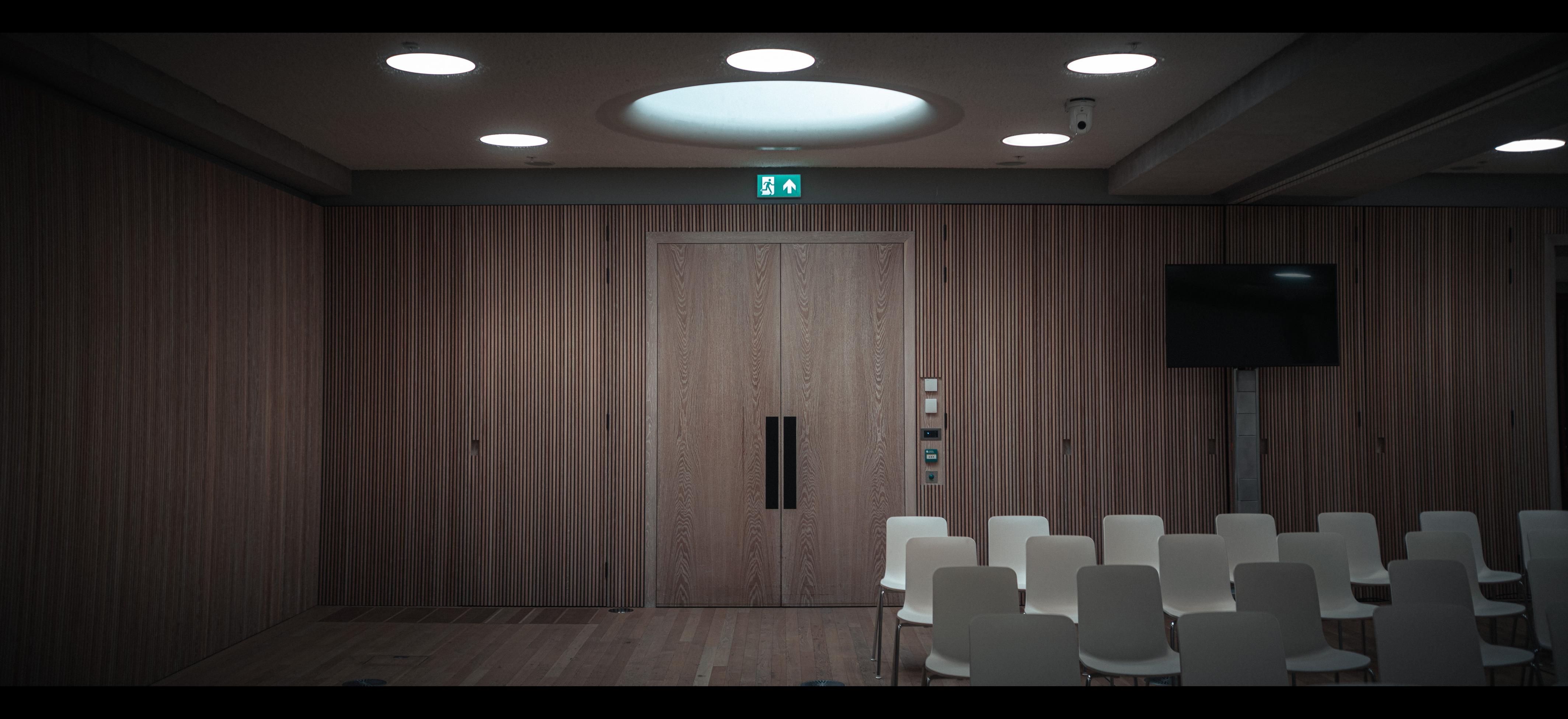 Rows of chairs in a wood grain lined room.