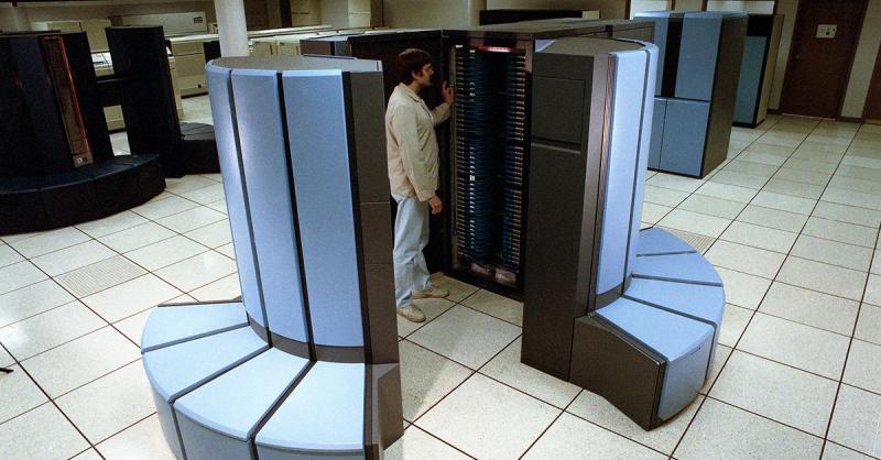 A person standing inside the circular section of a CRAY X-MP supercomputer in pale blue