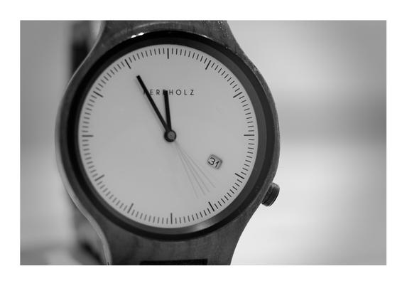 Schwarz-weiß Foto einer Uhr, die Zeiger stehen auf 5 vor 12 am 31. eines Monats. Der Sekundenzeiger ist wegen einer Belichtungszeit von mehreren Sekunden „in Bewegung“ abgebildet.