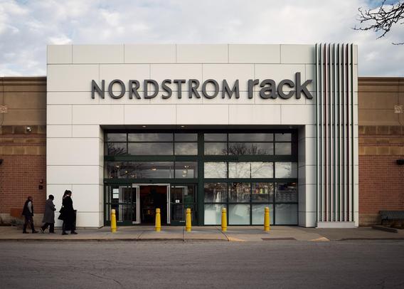 The image shows the front of a Nordstrom Rack at an outdoor shopping center called Old Orchard in Skokie. Three people stand in front. The surrounding is likely urban with the presence of modern shop signs and architecture.