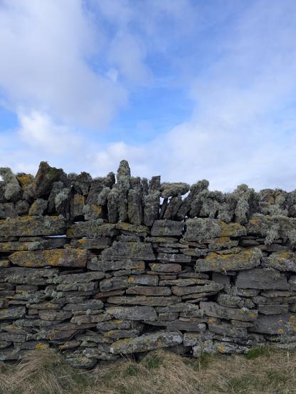 A ragged dry stone wall with awkwardly stacked rocks and a lot of lichen