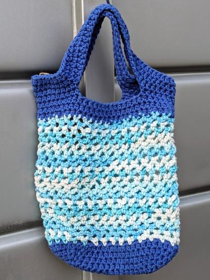 A crochet market bag in white and shades of blue.