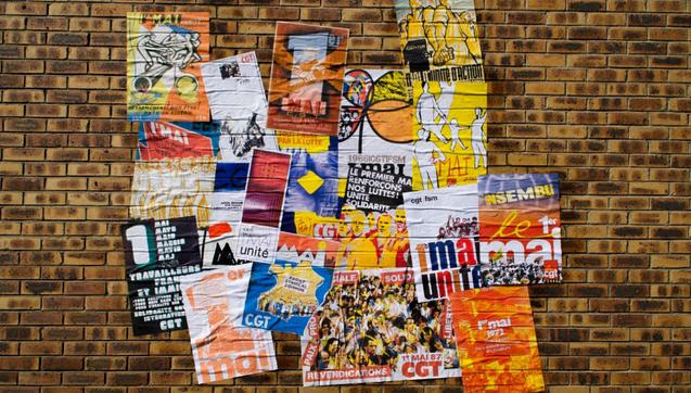 Visuel réalisé pour le premier mai 2025 : sur un mur de briques, collage d'anciennes affiches CGT du 1er mai, avec des messages en l'honneur des luttes, de la solidarité et des droits des salarié·e·s.
