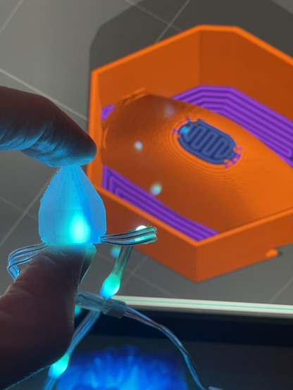 A 3d printed crystal shape internally illuminated by a cyan led, with a computer generated preview of a 3d print