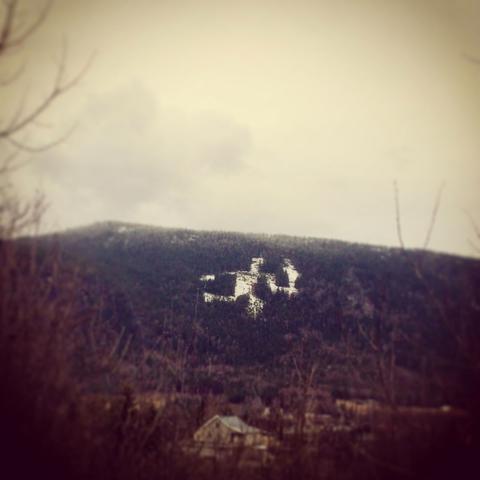 The image shows the Fakkelmannen (Olympic Torch Man) in Hafjell, Norway. It is a landmark—based on bronze age stone carvings—carved into the forest on the side of the valley, created ahead of the 1994 Lillehammer Winter Olympics. Hafjell hosted the slalom and giant slalom events during the Games.