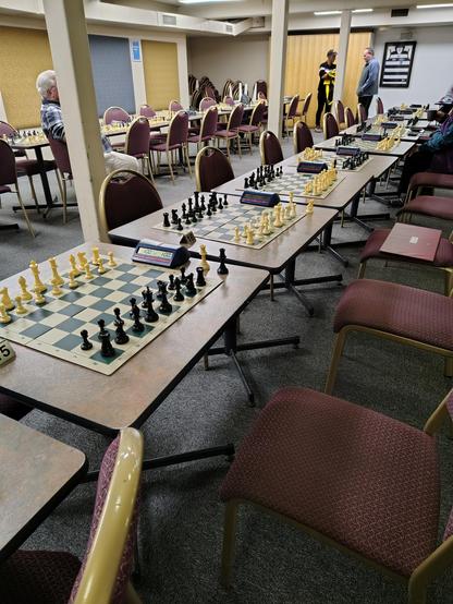 Two rows of large chess boards on tables set up ready to play.
