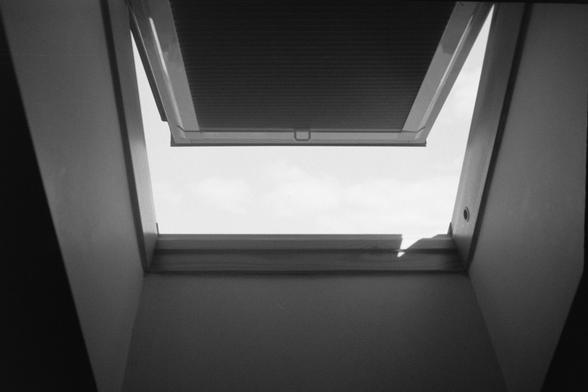 A black and white photograph of a half opened velux window.