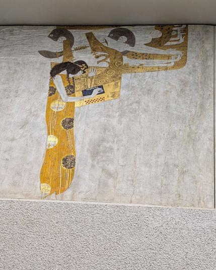detail of Gustav Klimt's Beethovenfries in the Wiener Secession: a golden figure with a musical  instrument, at the top floating figures