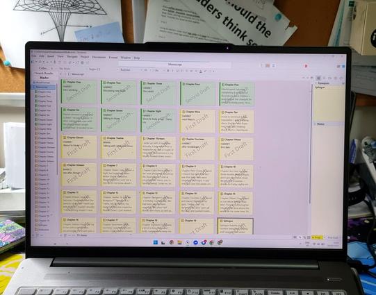 Photo of an opened laptop. On the screen are a number of corkboard cards (Scrivener). Eight are coloured green (2nd draft) the remaining 22 yellow shown are 1st draft.