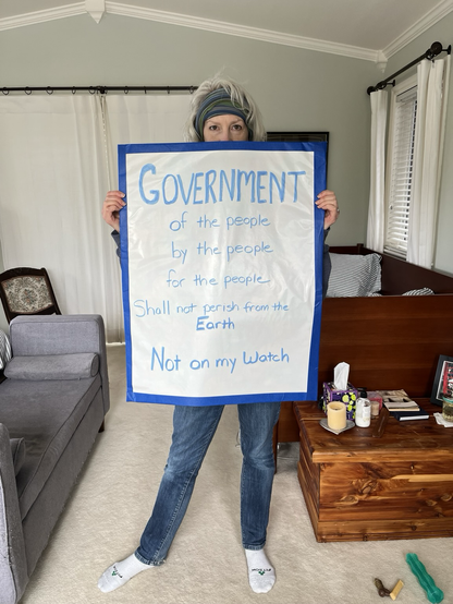 Me holding my protest sign which reads, “Government of the people, by the people, for the people shall not perish from the Earth. Not on my watch.”