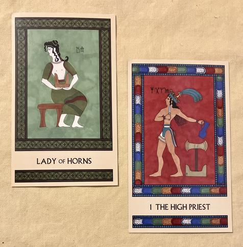 Two Minoan Tarot cards side by side on a pale yellow background. The Lady of Horns is painted in shades of green and brown. A Minoan woman sits on a stool, facing right but with her head turned back toward the left. She holds a pair of sacred horns in her lap. The High Priest has a bright multicolored border. It shows a Minoan man in a loincloth and a plumed hat, standing, facing left. He holds a dagger in his right hand and a pitcher in his left hand. Next to him stands a pair of sacred horns with a labrys mounted atop them.