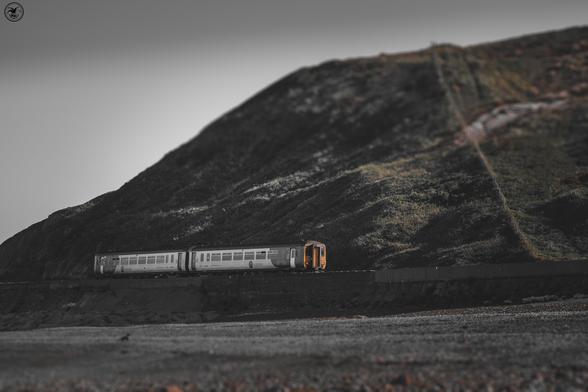 Two carriage train in front of cliffs on coastal tracks