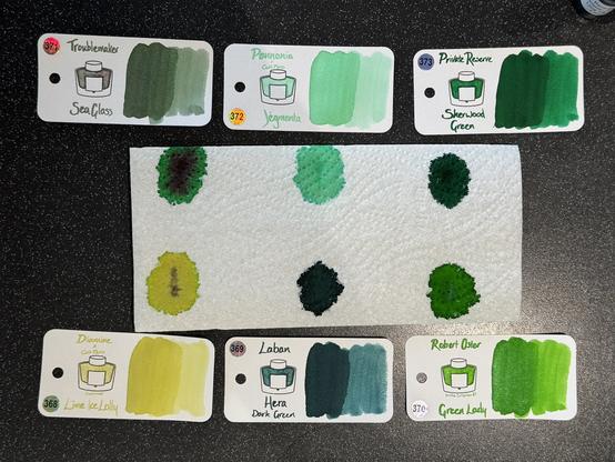 Cult Pens April Ink Sub Box swatches + paper towel faux-chromatography. Troublemaker Sea Glass, Pennonia × Cult Jégmenta, Private Reserve Sherwood Green, Diamine × Cult Lime Ice Lolly, Laban Hera Dark Green, & Robert Oster Green Lady