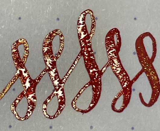 A close-up of handwritten glittering red cursive lettering on white dot grid paper featuring interconnected loops and swirls.