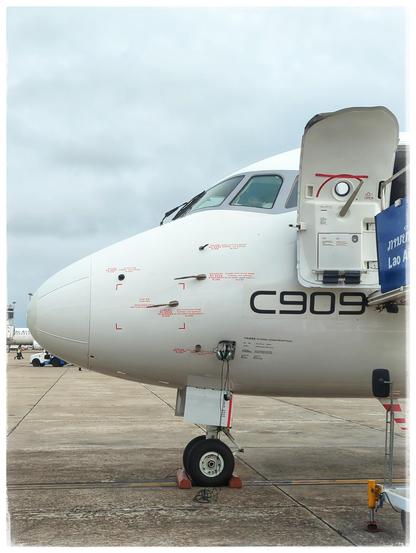 The nose and cockpit of an aircraft. The open door can be seen, stairs going up to the entrance. In large letters, the type of the aircraft is drawn on the body: C909