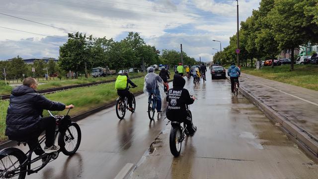 Einige Radfahrende fahren im Demoverband auf einer Straße. Man erkennt, dass es regnet.