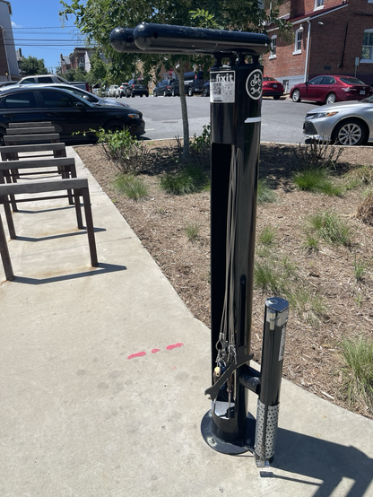 A freestanding bike stand made by the company Dero stands at the edge of a park.