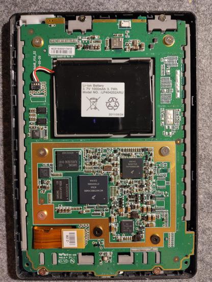 Photo showing the insides of a Kobo touch ereader from the back. Lots of circuits, chips and a large black battery at the top.