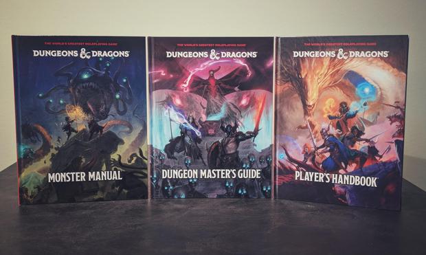 Kolme D&D kirjaa pöydällä: Monster Manual, Dungeon Master's Guide js Player's Handbook