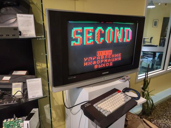 A large CRT television connected to a russian computer displaying the title screen / menu for the game "Second" in red and green.