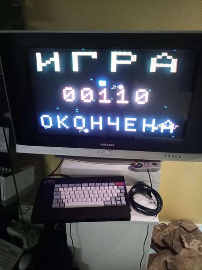 The same computer and TV later at night, displaying "GAME OVER" (ИГРА ЗАКОНЧЕНА) in Russian, with a final score of 00110.