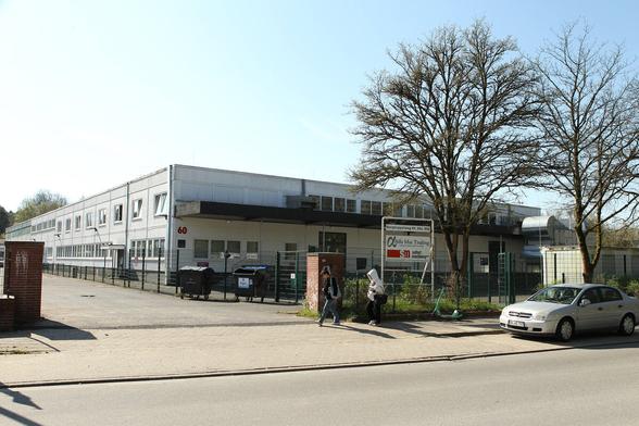 zweigeschossige Gewerbehalle hinter einem Zaun